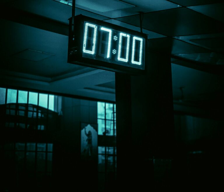 Digital clock showing 7:00 with reflection in a modern indoor setting, creating a moody atmosphere.